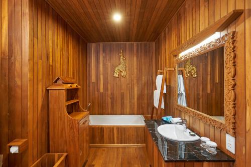 KMA Inle Hotel في نياونغ شوي: حمام خشبي مع حوض استحمام ومغسلة