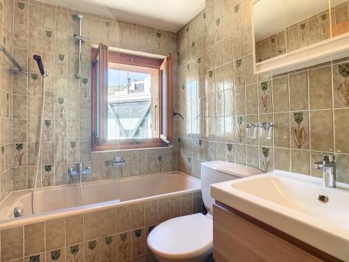 a bathroom with a toilet and a tub and a sink at Emeraude 319 in Verbier