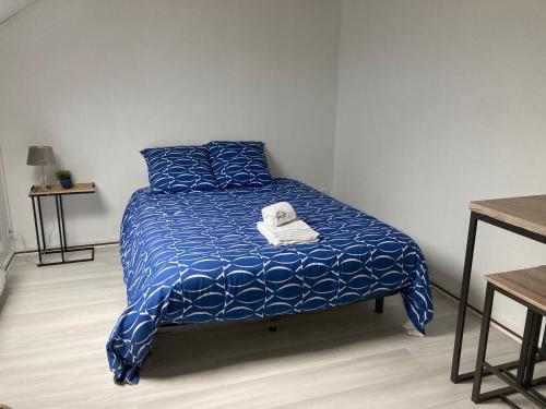 a bed with a blue comforter with a towel on it at LE STUDIO COLBERT - plein centre à petit prix - in Rethel