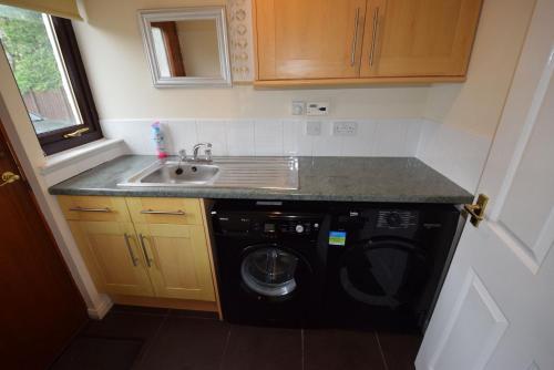 a kitchen with a sink and a washing machine at Ridgeview Villa - Partial loch view in Lochgoilhead