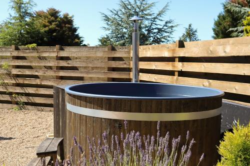 a wooden fence with a wooden tub in a garden at Bunnahahbain - Two Bedroom Luxury Log Cabin with Private Hot Tub in Berwick-Upon-Tweed