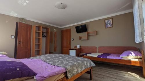 a bedroom with two beds and a tv on the wall at Baltazar in Łeba