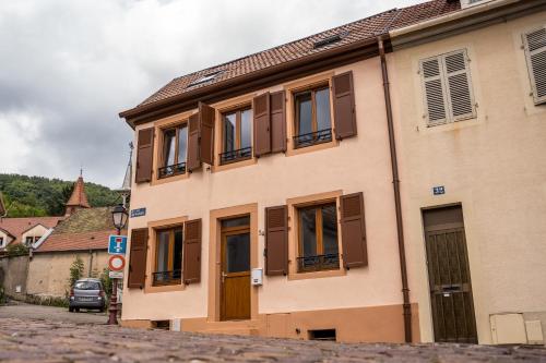 un bâtiment avec des fenêtres à volets marron dans une rue dans l'établissement Gîte Chez Lucile, à Thann