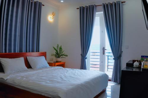 a bedroom with a bed with blue curtains and a window at Kampot Coco Guest House in Kampot