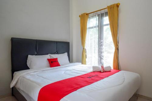 a bed with a red blanket and a window at RedDoorz @ Kratonan Solo in Solo