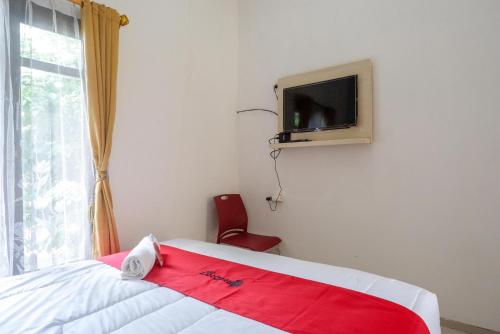 a bedroom with a bed and a tv on the wall at RedDoorz @ Kratonan Solo in Solo