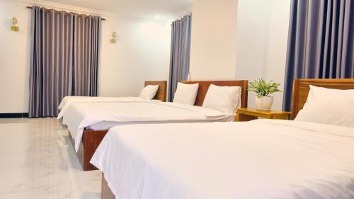 a hotel room with three beds with white sheets at Kampot Coco Guest House in Kampot