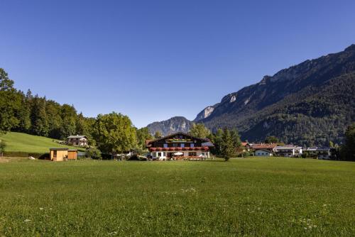 a large green field with houses and mountains in the background at Wassererlehen in Bischofswiesen
