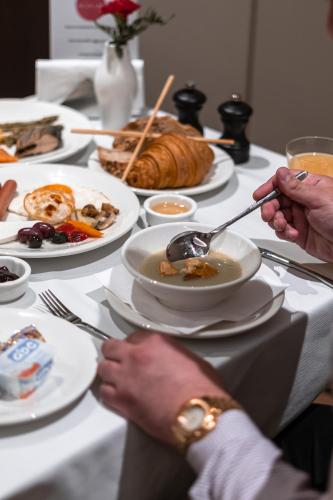 a table full of plates of food with people eating at Hotel MANAMI in Pristina