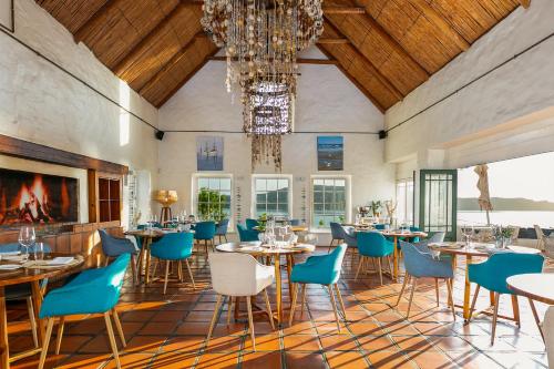 uma sala de jantar com mesas e cadeiras e um lustre em The Farmhouse Hotel em Langebaan