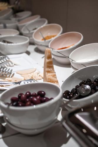 a table topped with white bowls of grapes and spoons at Hotel MANAMI in Pristina