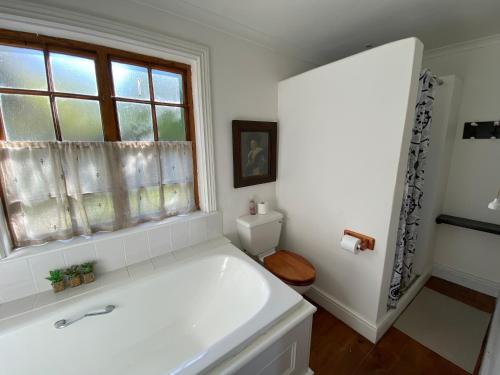 biała łazienka z wanną i oknem w obiekcie The Blue House w mieście Stanford