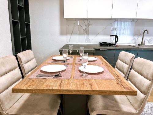 a wooden table with plates and wine glasses on it at Luxury apartment Struga in Struga
