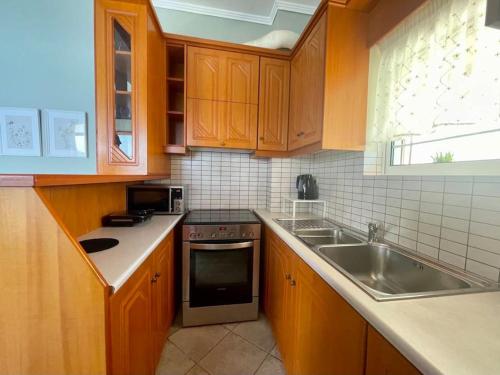 a kitchen with wooden cabinets and a sink and a stove at Seaside Apartment in Glyfada-Trizonia in Glyfada Fokidas