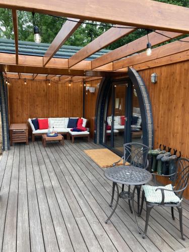 a wooden deck with a couch and a table and chairs at Bedrule Old Manse Glamping in Hawick