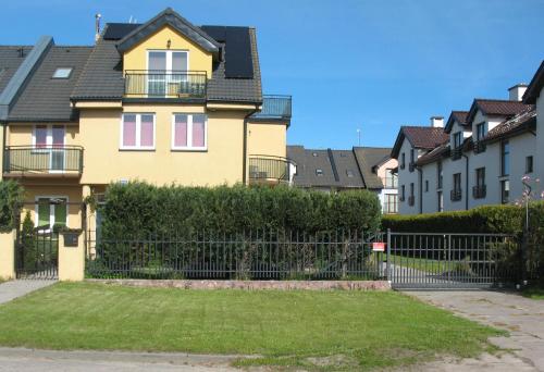 una casa amarilla con una valla en un patio en Baltazar, en Łeba