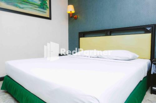 a large bed in a room with a white bedspread at Hotel Yasmin Makassar Mitra RedDoorz in Makassar