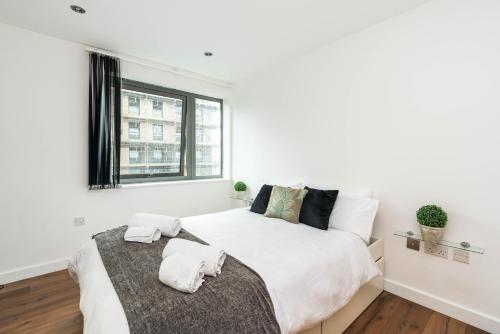a white bedroom with a large bed and a window at Direct Tube Links to Central London , Walk to Station one bedroom flat in Greater London, ID required in London