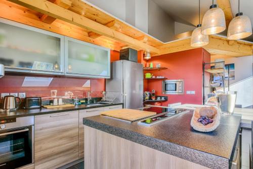 une grande cuisine avec des murs rouges et des placards en bois dans l'établissement Panorama du Bellay - Welkeys, à Annecy-le-Vieux