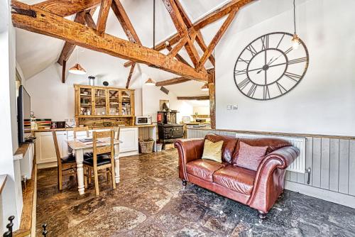 a living room with a couch and a clock on the wall at Guest Homes - Snodsbury Barn in Upton Snodsbury