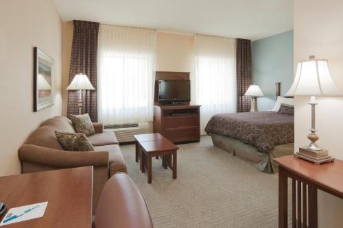 a hotel room with a bed a couch and a television at Staybridge Suites Lafayette-Airport, an IHG Hotel in Lafayette