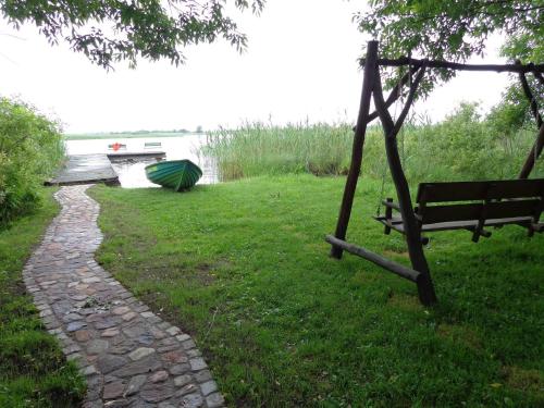 a swing and a bench in a park at Czerwony domek nad samym jeziorem in Mikołajki