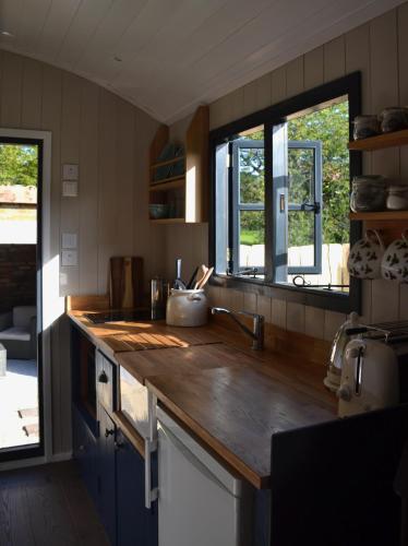 a kitchen with a wooden counter top and two windows at Large Luxury Shepherds Hut with Hot Tub nr Bath in Bristol