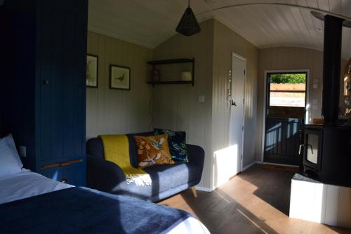 a bedroom with a couch and a tv in it at Large Luxury Shepherds Hut with Hot Tub nr Bath in Bristol
