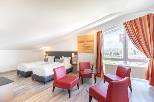 um quarto de hotel com uma cama e cadeiras vermelhas em Select Hotel A1 Bremen-Stuhr em Stuhr