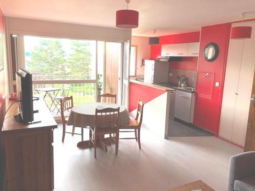 a kitchen with red cabinets and a table and a table and chairs at GRAND Appart 46m² en ville à 10 mn de la plage in Cabourg