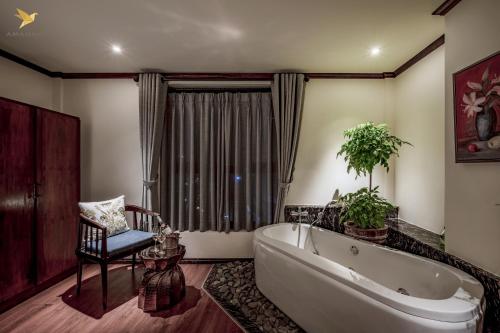 uma casa de banho com uma banheira grande e uma cadeira. em Amanaki Saigon Boutique Hotel em Ho Chi Minh