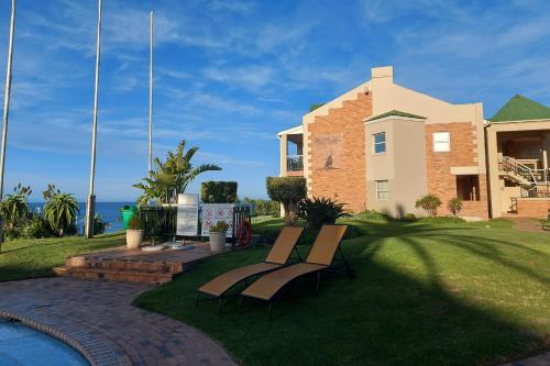 a couple of benches sitting in the grass in front of a house at First Group Brookes Hill Suites in Summerstrand