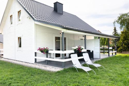a white house with a picnic table and chairs at Jantar Domki Comfort oraz Comfort Wellness Zone sauna jacuzzi in Jantar