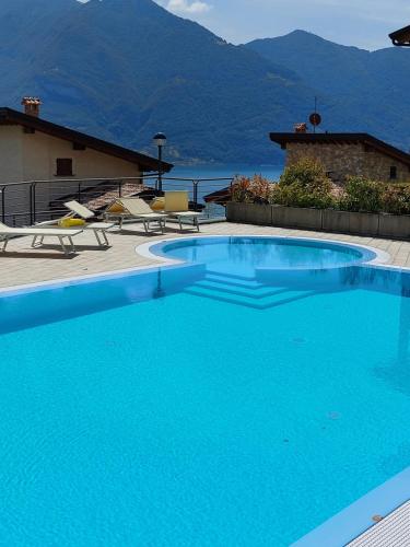 une grande piscine bleue avec des montagnes en arrière-plan dans l'établissement Iseo Lake Villa con vista lago e piscina, à Costa Volpino