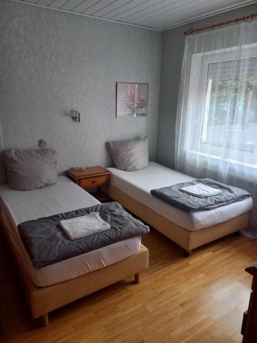 two twin beds in a room with a window at Gästehaus Hein in Emsbüren