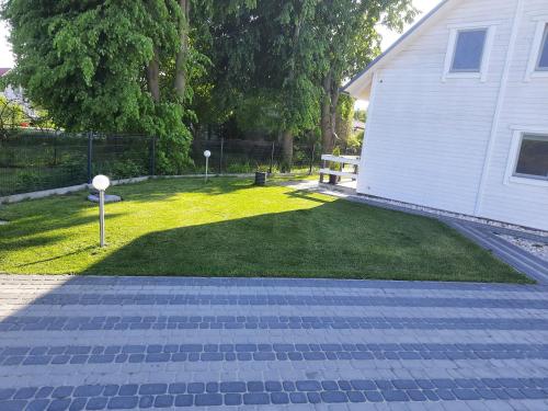 a yard with a house and a lawn with a bench at Jantar Domki Comfort oraz Comfort Wellness Zone sauna jacuzzi in Jantar