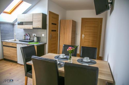 a kitchen and dining room with a wooden table and chairs at Apartamenty Tilia Laskowa - Zator in Laskowa