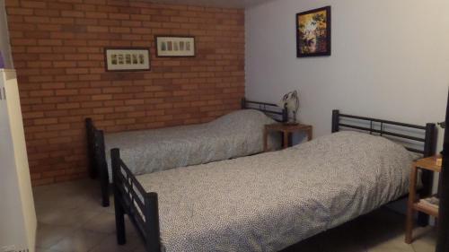 a bedroom with two beds and a brick wall at B&B Piccardie in Emlichheim