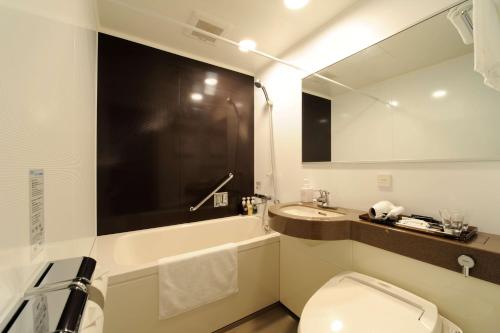 a bathroom with a sink and a toilet and a mirror at Best Western Hotel Fino Osaka Shinsaibashi in Osaka