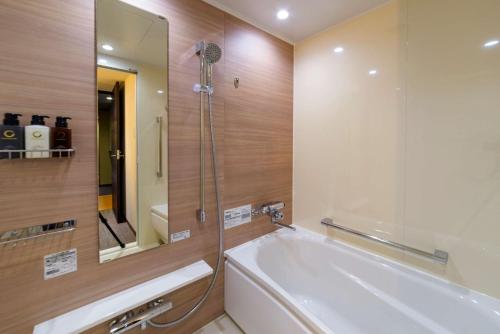 a bathroom with a bath tub and a mirror at Best Western Plus Hotel Fino Chitose in Chitose