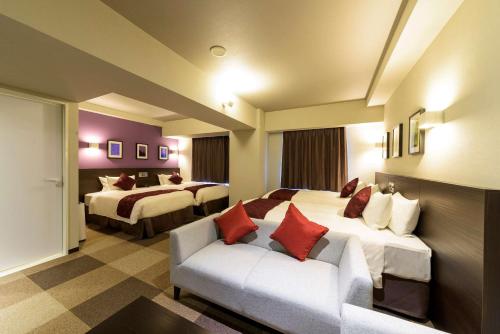 千歳市にあるベストウェスタンプラスホテルフィーノ千歳のベッド2台とソファが備わるホテルルームです。