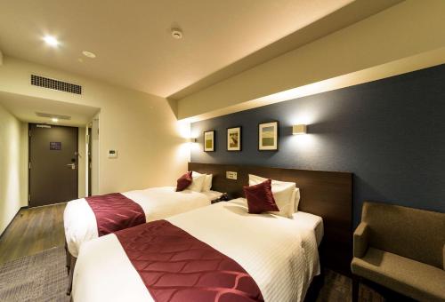 a hotel room with two beds and a chair at Best Western Plus Hotel Fino Chitose in Chitose