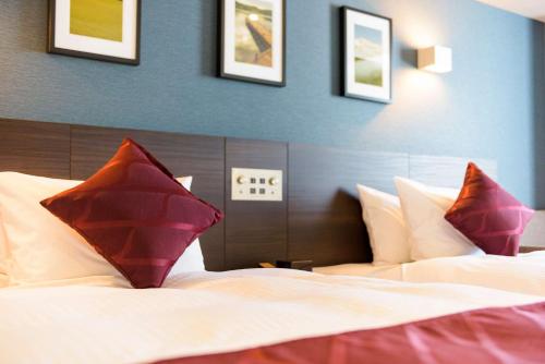 a bedroom with a bed with red pillows on it at Best Western Plus Hotel Fino Chitose in Chitose