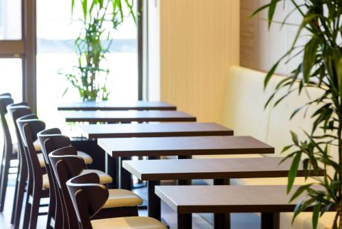 a row of wooden tables and chairs with plants at Best Western Plus Hotel Fino Chitose in Chitose
