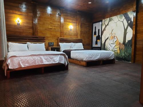 a bedroom with two beds and a painting on the wall at Mountainmist wooden cottages in Ramakkalmedu