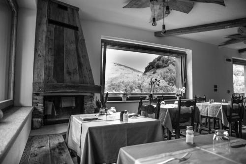 ein Restaurant mit Tischen, einem Kamin und einem Fenster in der Unterkunft Hotel Edelweiss in Limone Piemonte