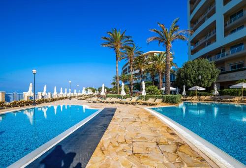 uma piscina num resort com palmeiras e edifícios em Radisson Blu Resort & Spa, Malta Golden Sands em Mellieħa