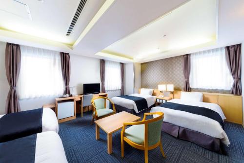 大阪市にあるシュアステイ プラス ホテル by ベストウェスタン 新大阪のベッド3台とテレビが備わるホテルルームです。