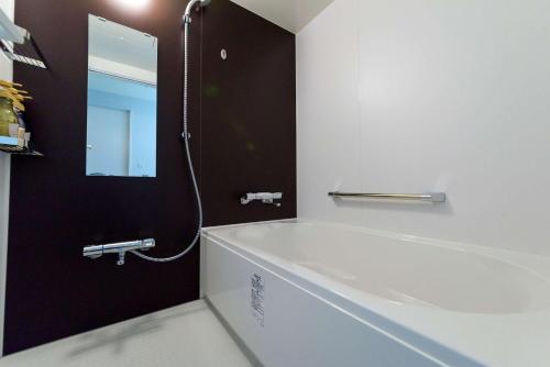 a bathroom with a bath tub and a mirror at SureStay Plus Hotel by Best Western Shin-Osaka in Osaka