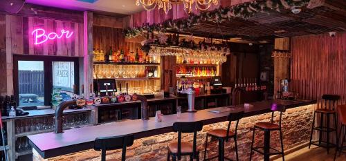 a bar with bar stools and a neon sign at The Waterside Bar, Rooms & Restaurant in Manchester